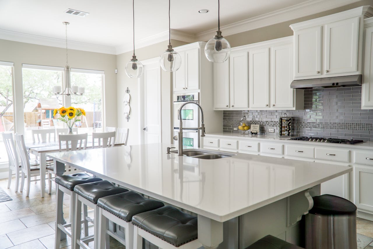 services-05 Spacious modern kitchen with white cabinets and island in natural light.